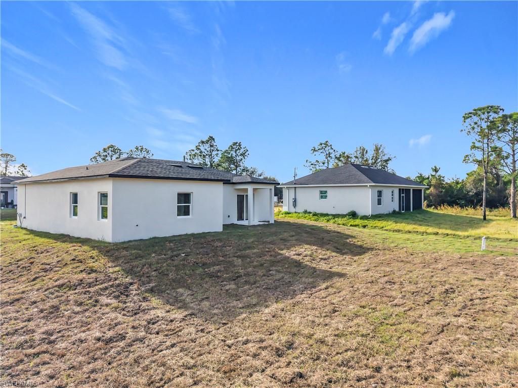 Rear view of property with a lawn, stucco siding, and a patio