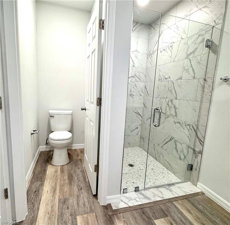 Bathroom featuring light wood finished floors and a marble finish shower