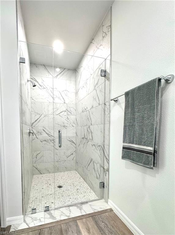 Full bath featuring a marble finish shower and wood finished floors