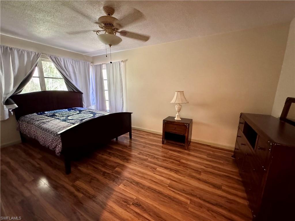 Wood-finish flooring with a ceiling fan light fixture and multiple windows