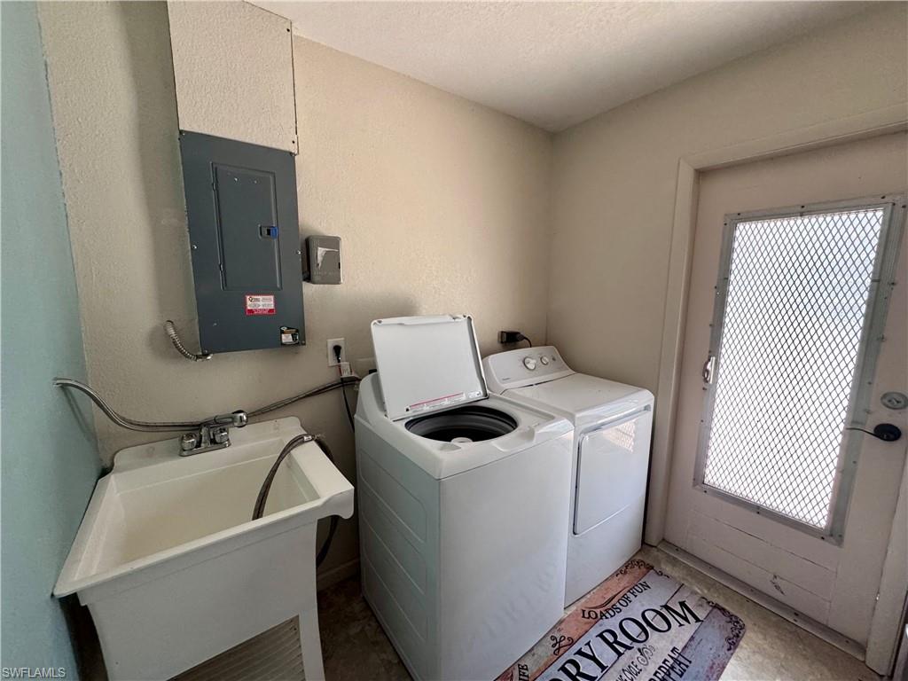 Utility sink with stainless steel faucet, wall-mounted electrical panel, and an exterior door with a security screen