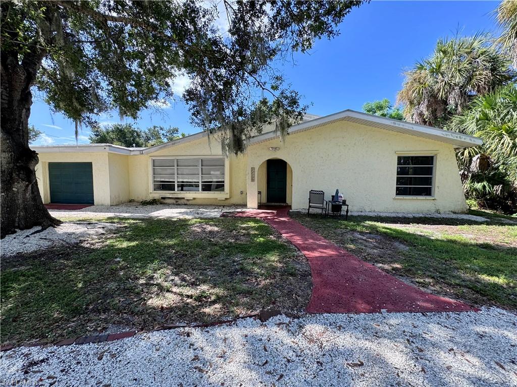 Charming single-story home featuring a cream stucco exterior with arched entryway, metal-framed windows, and an attached garage