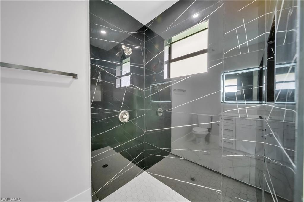 Walk-in shower with black tile surround, hexagonal tile floor, and polished chrome fixtures