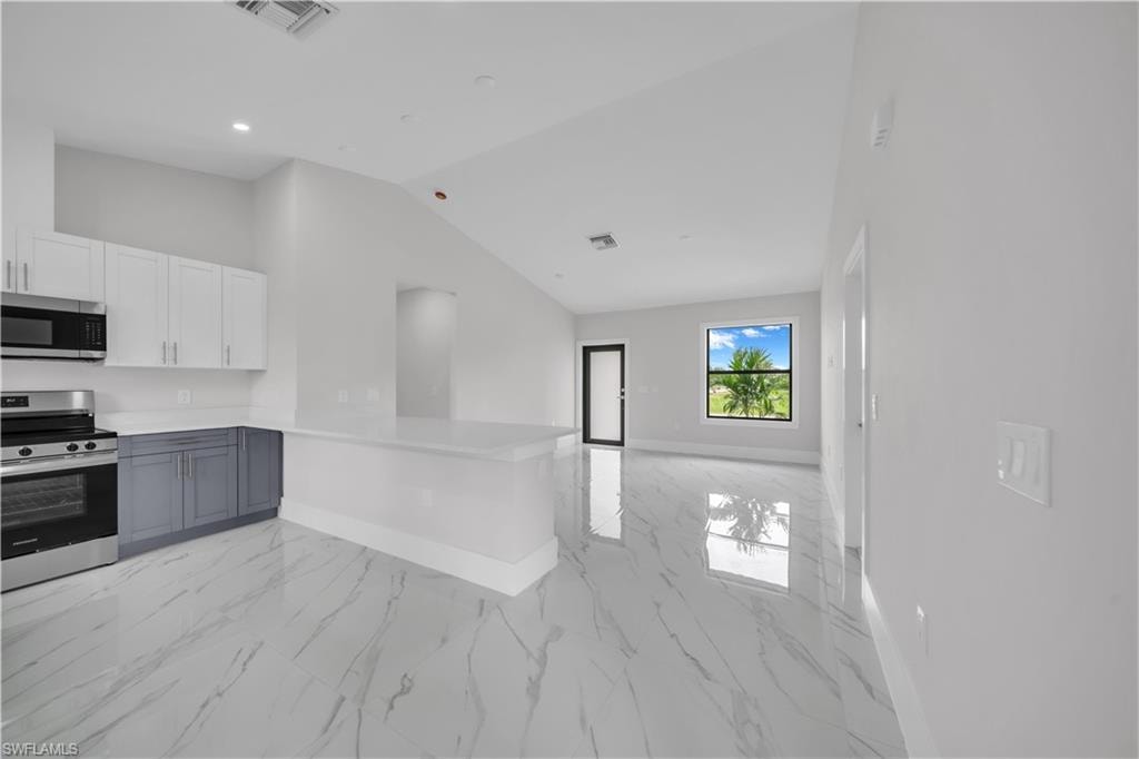 Open-concept layout featuring a kitchen island, stainless steel appliances, and large format tile flooring