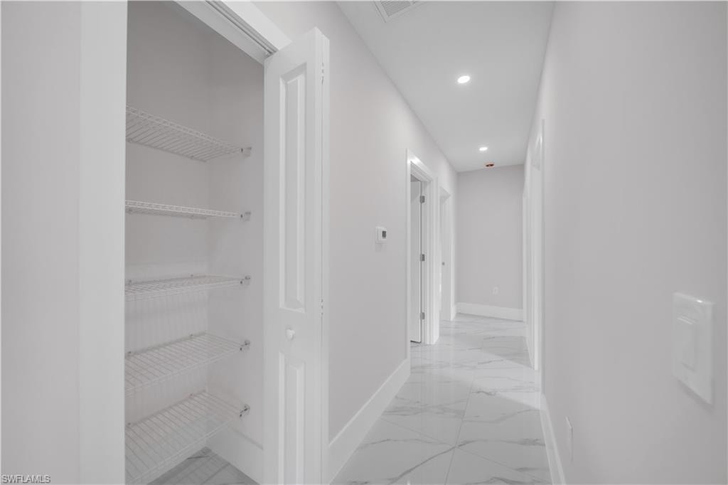 Hallway featuring recessed lighting, white walls, and marble-look flooring