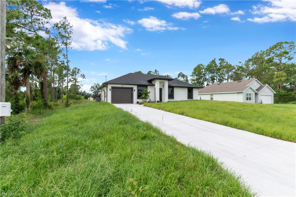 Contemporary single-story residence featuring a dark shingle roof, white exterior siding, and an attached garage with a dark panel door