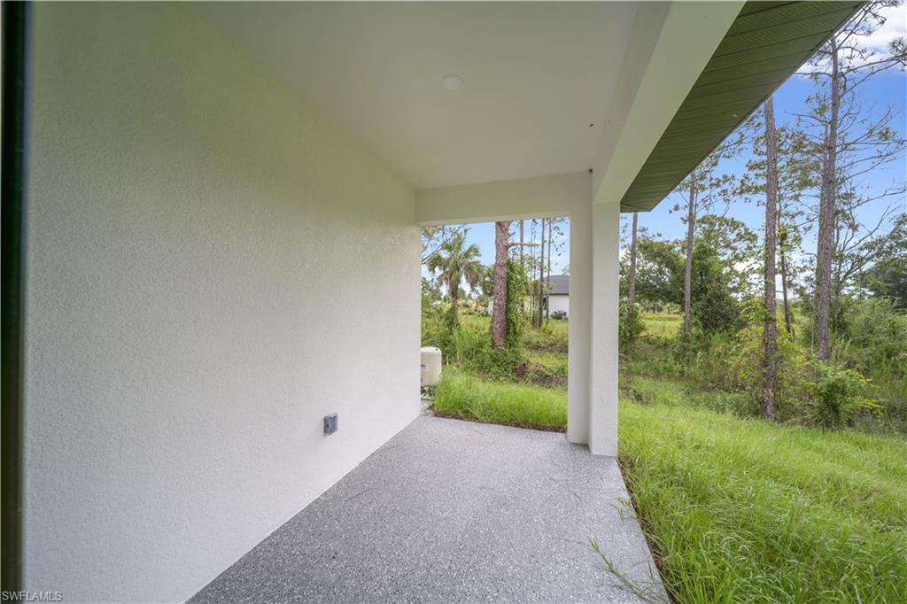 Covered outdoor patio with a textured concrete floor and stucco exterior walls