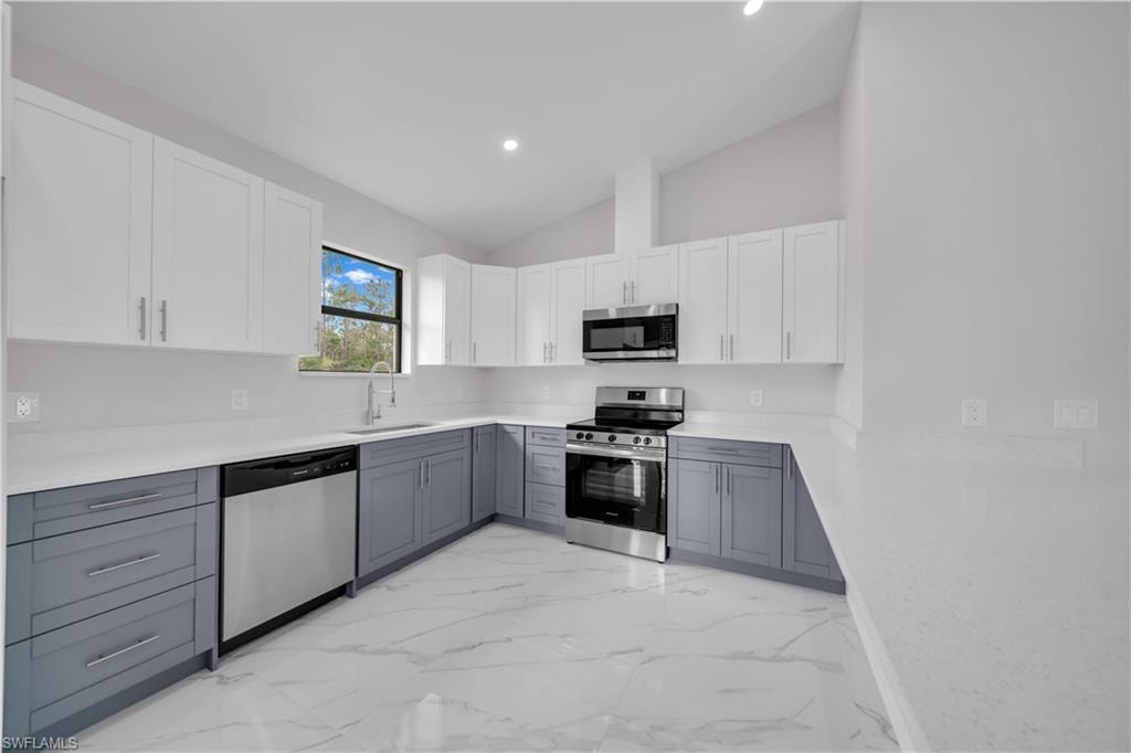 Modern kitchen featuring two-tone cabinetry, stainless steel appliances, a single basin sink, and white countertops