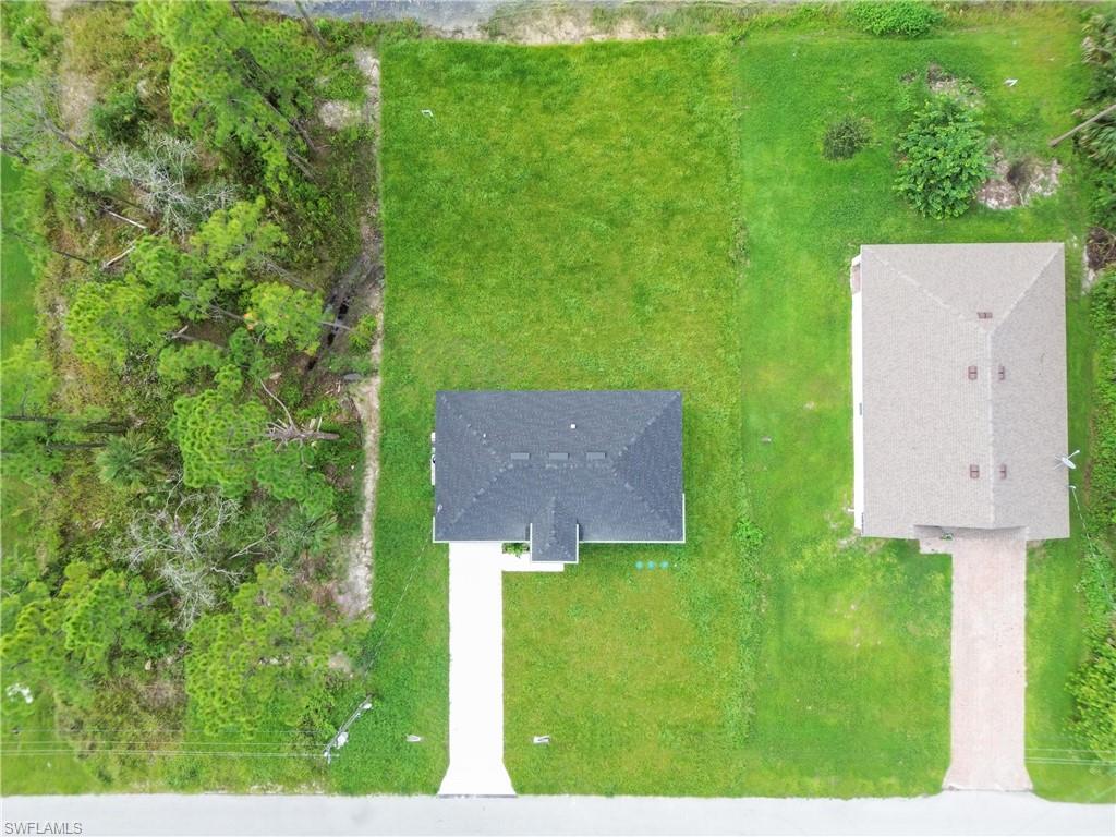 Newly constructed residence featuring a dark shingle roof and a concrete driveway