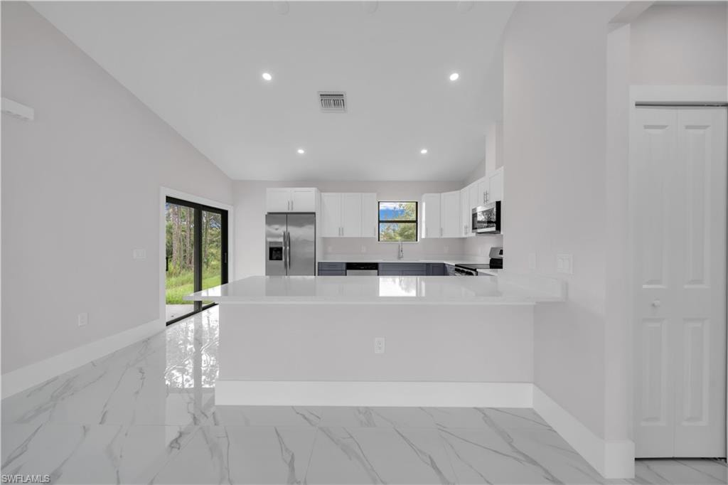 Kitchen featuring white cabinetry, stainless steel refrigerator, white countertops, and recessed lighting
