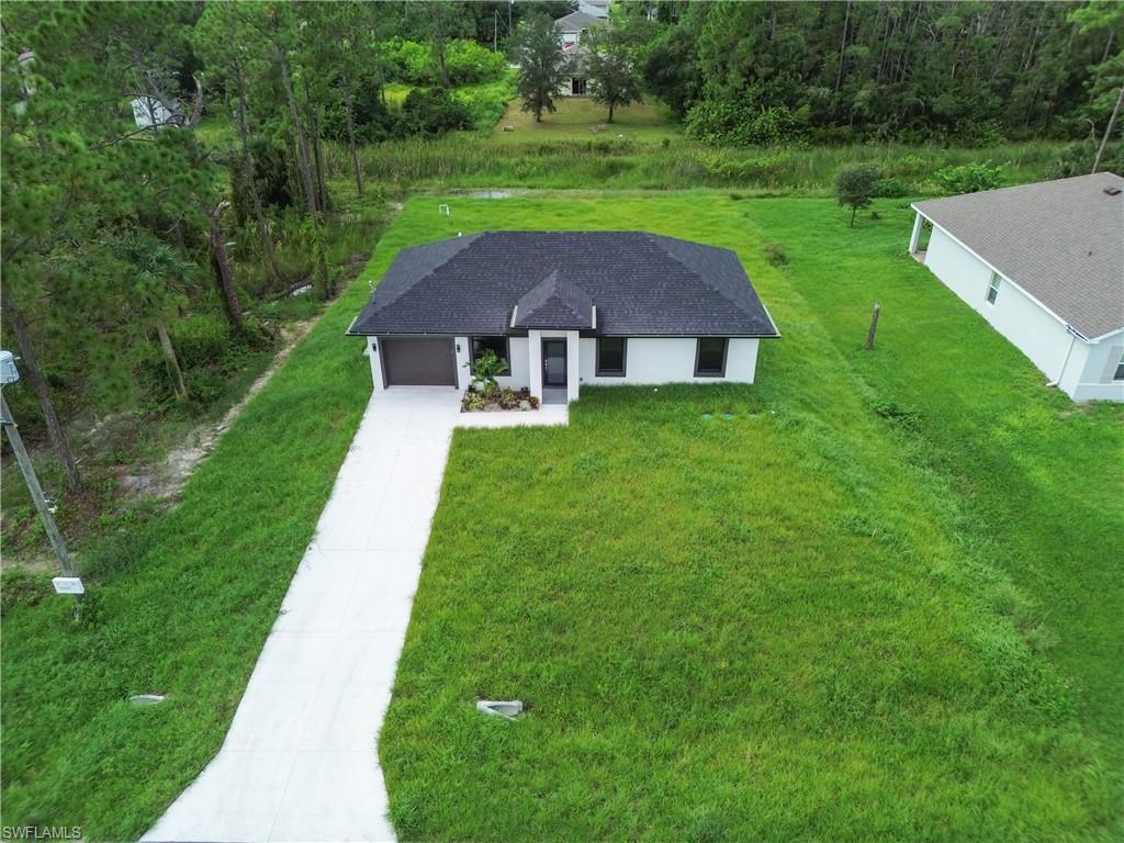 Single-story residence featuring a dark shingle roof, white exterior, attached garage, and a concrete driveway
