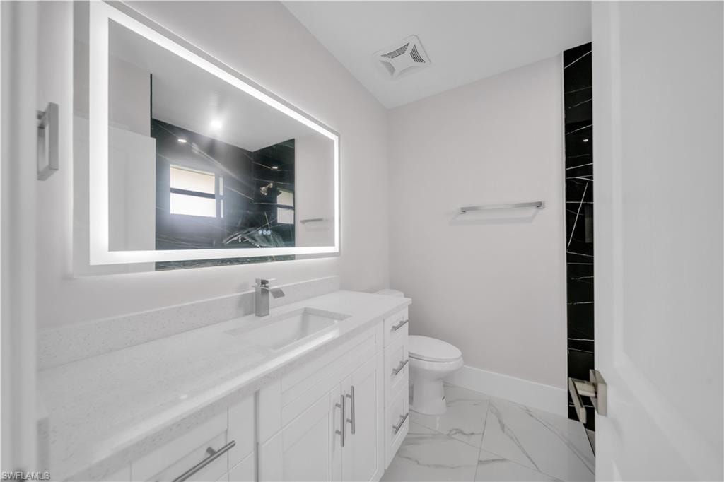 Vanity with a rectangular undermount sink, a chrome single-lever faucet, and a large illuminated mirror