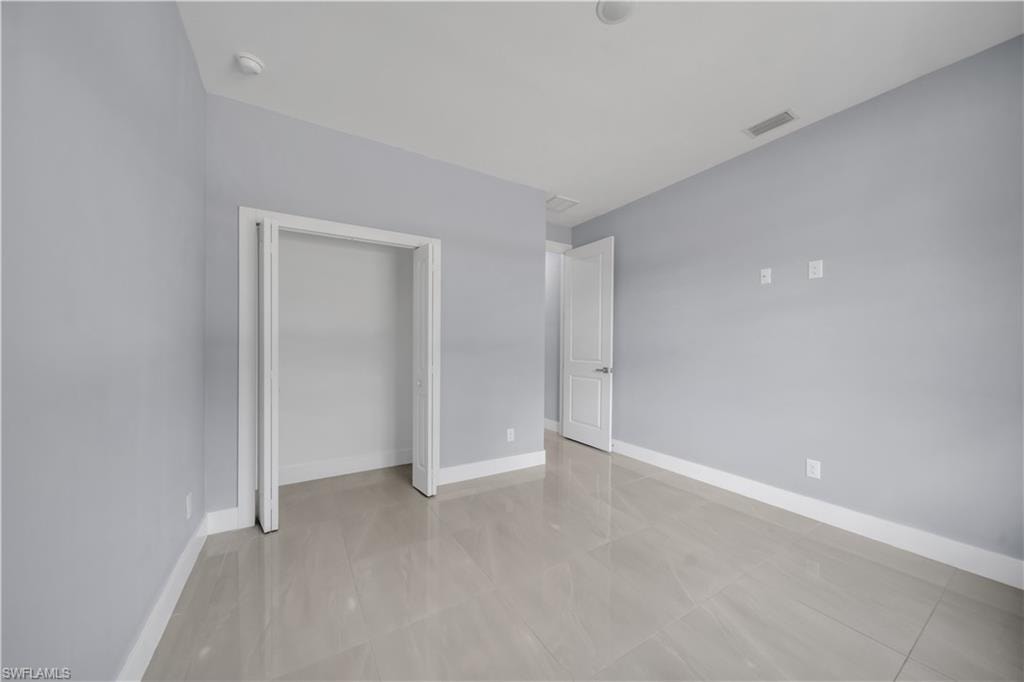 Light gray wall finish with a white ceiling, recessed lighting, and a white door with silver hardware
