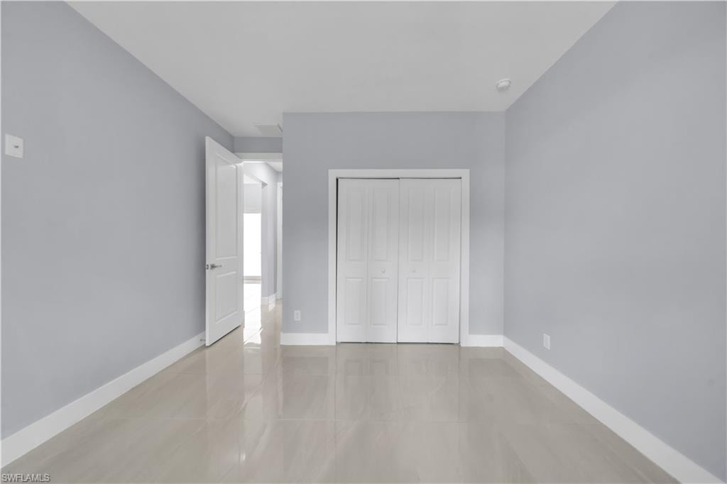 Light-colored wall paint with white trim, gloss tile flooring, and bi-fold closet doors