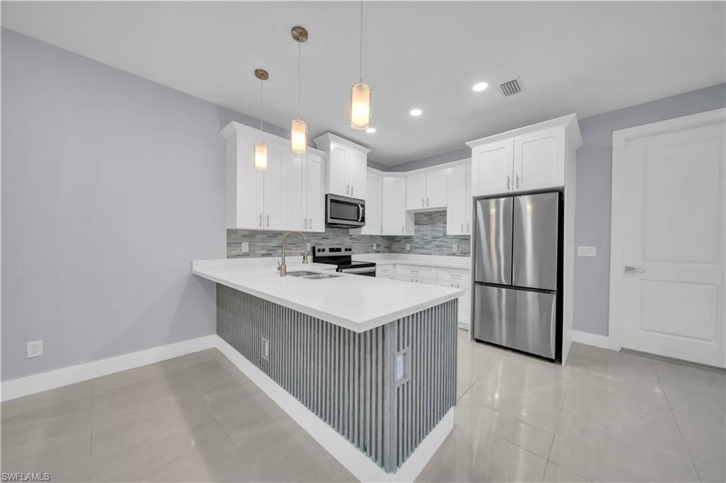 Contemporary kitchen featuring white cabinetry, stainless steel appliances, a white island countertop, and tile flooring