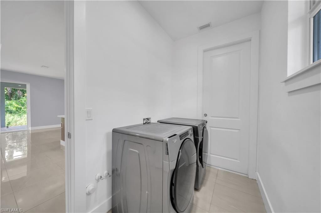 Dedicated laundry area with light tile flooring and white walls