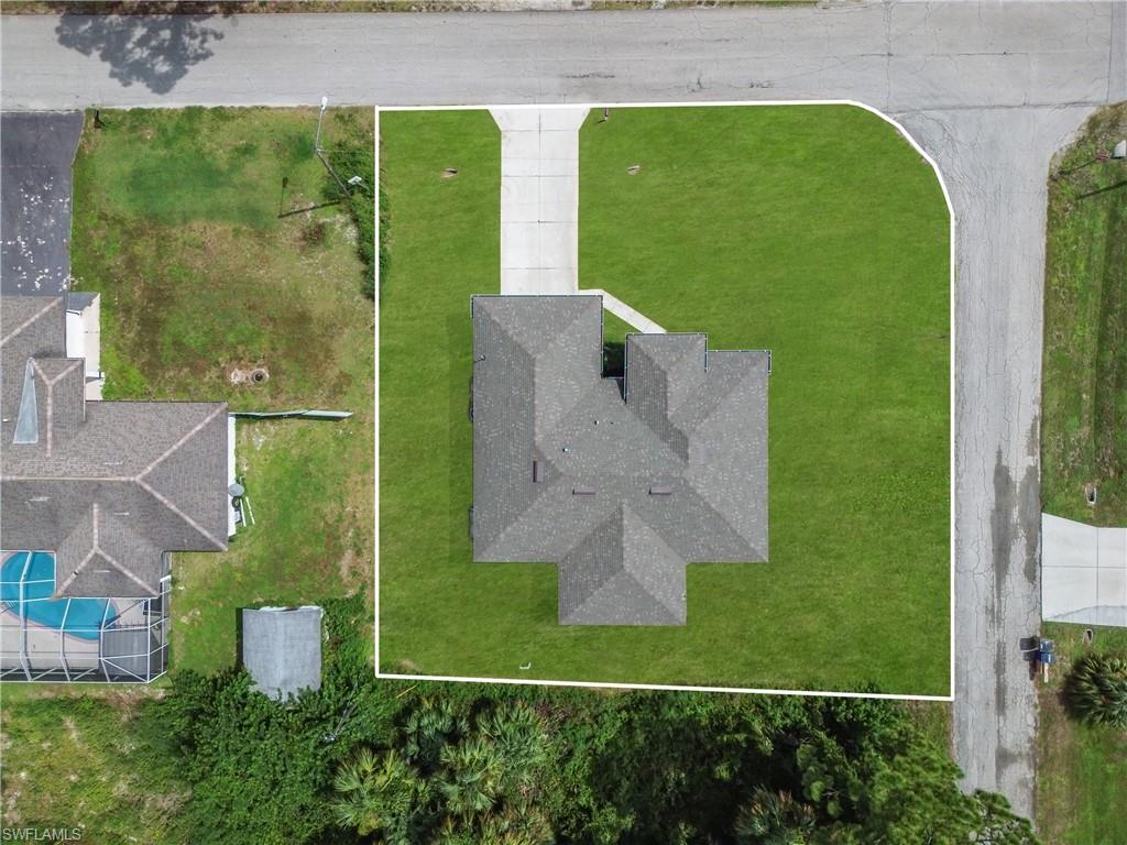 Pitched shingle roof structure with a concrete driveway and surrounding green lawn