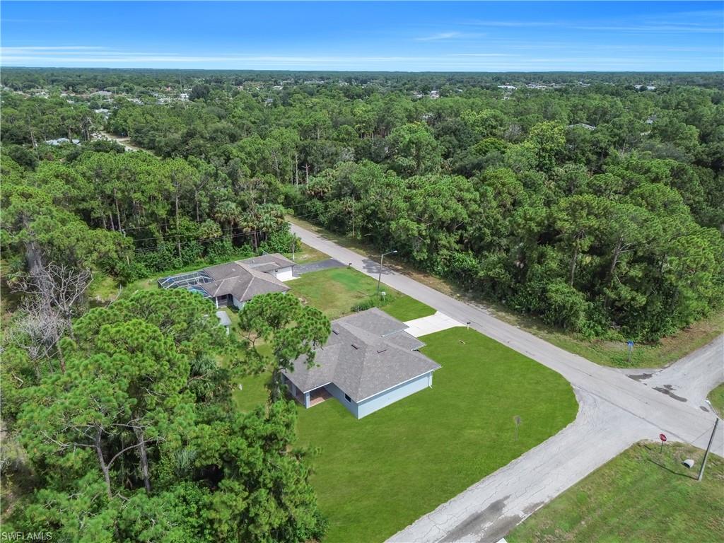 Property featuring a lush green lawn, mature trees, and a paved driveway
