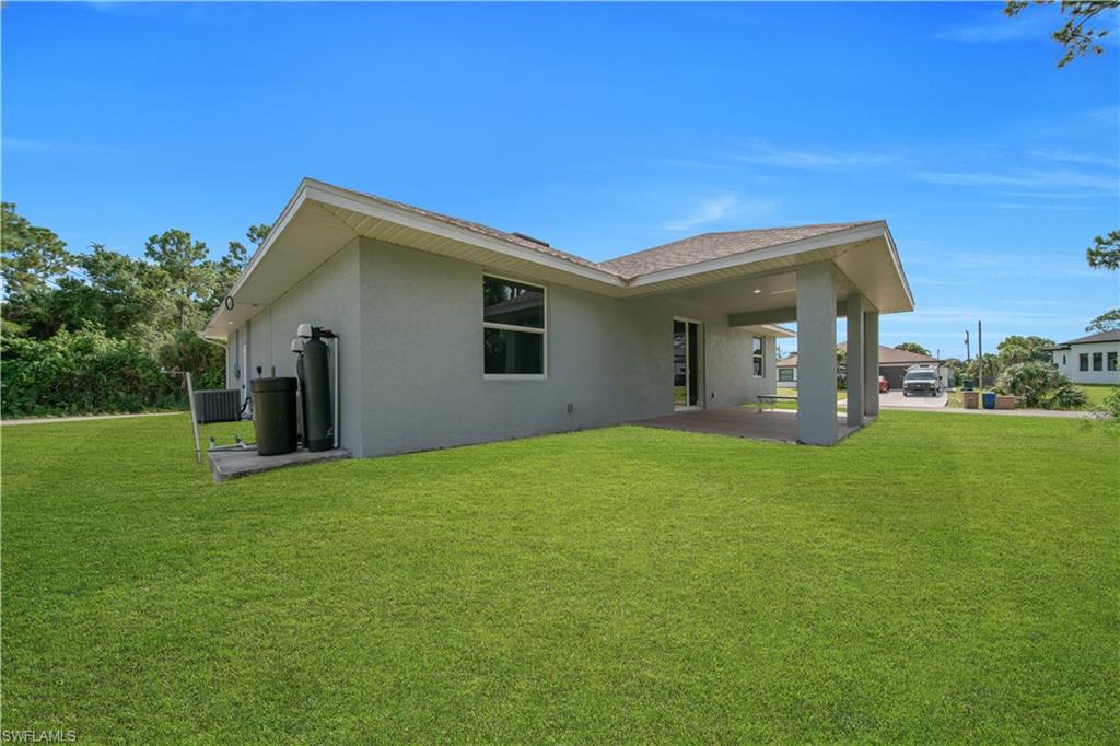 Expansive green lawn, covered patio, and stucco exterior