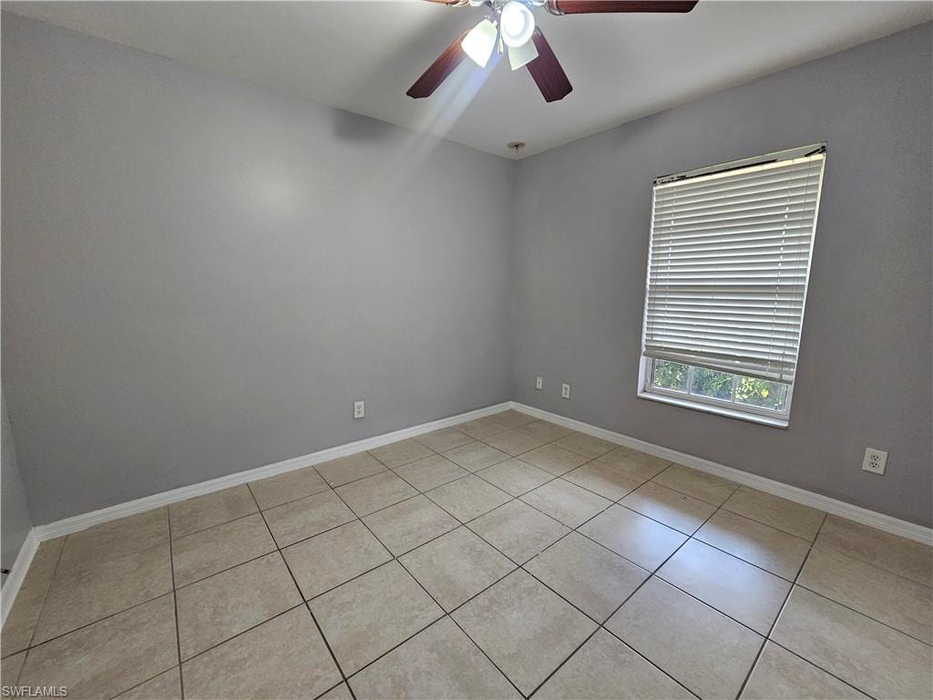 Spacious bedroom featuring tile flooring, neutral wall finishes, ceiling fan with integrated lighting, and large window with horizontal blinds allowing natural light throughout the room