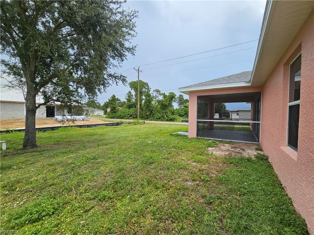 Screened patio with a textured exterior wall, featuring a window and an adjacent grassy area