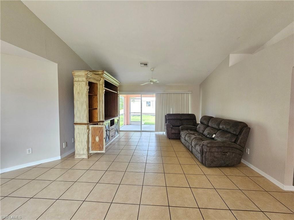 Vaulted ceilings with a ceiling fan, neutral wall colors, tiled flooring, and sliding glass doors to outdoor space