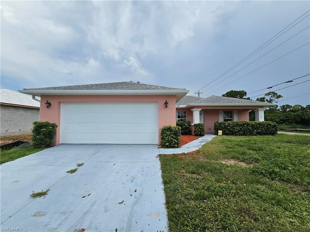 Pink stucco exterior with white trim, two-car garage, covered entry porch with columns, and a concrete driveway