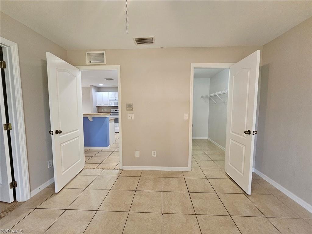 Spacious primary living area featuring neutral wall finishes, tile flooring throughout, and multiple doorway entries