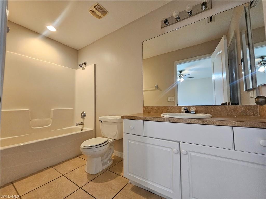 Bathroom featuring a tub/shower combination, white vanity with integrated sink, full-width mirror, and tiled flooring