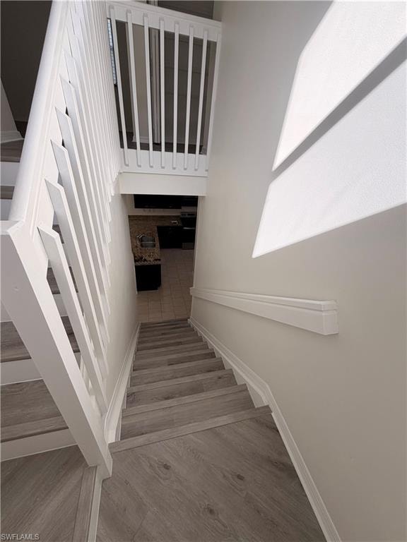 Staircase featuring wood-finish treads, white painted risers, white balusters, and a white handrail