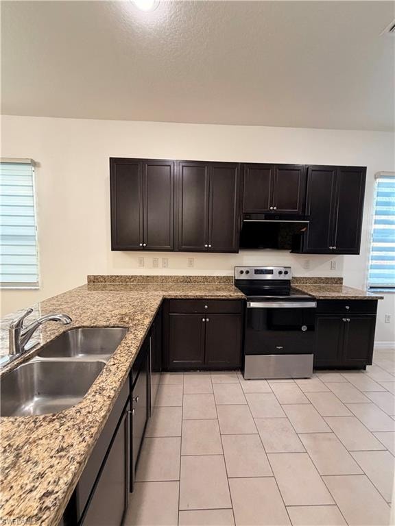U-shaped kitchen featuring dark wood-finish cabinetry, granite-finish countertops, stainless steel dual basin sink, and a black and stainless steel range