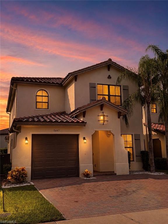 Stucco exterior with a tile roof, arched entryway, and a paved driveway