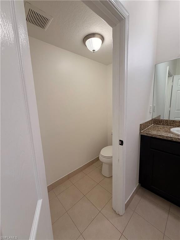 Powder room featuring a toilet, ceiling-mounted light fixture, and tile flooring