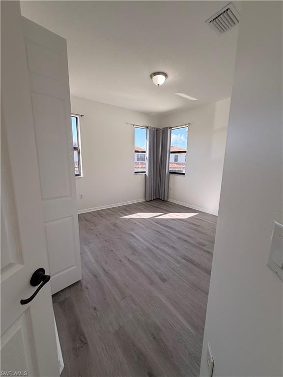 Neutral wall finishes, wood-finish flooring, two corner windows, and an overhead flush mount light fixture
