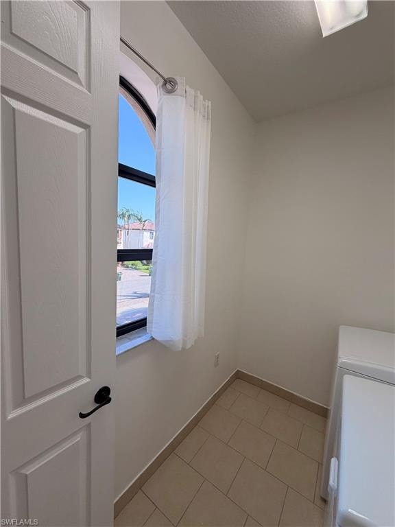 Arched window with black framing, tile flooring, white interior door with black hardware, and light-toned walls