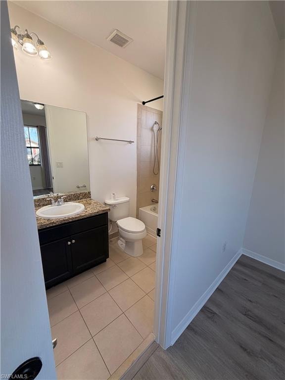 Bathroom featuring a dark wood-finish vanity with a light-toned countertop, a rectangular undermount sink, and tile flooring