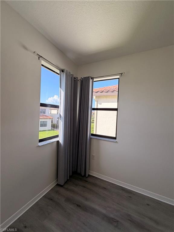 Wood-finish flooring with white baseboards, light-toned walls, and multiple windows