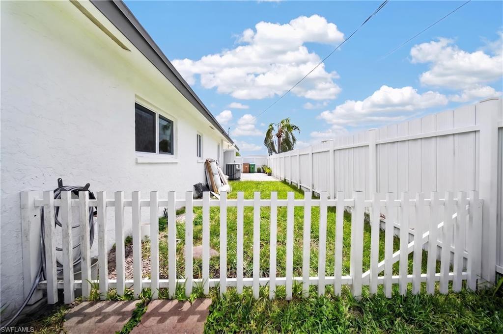 White stucco exterior with a dark fascia, a white picket fence, and a full-height white privacy fence