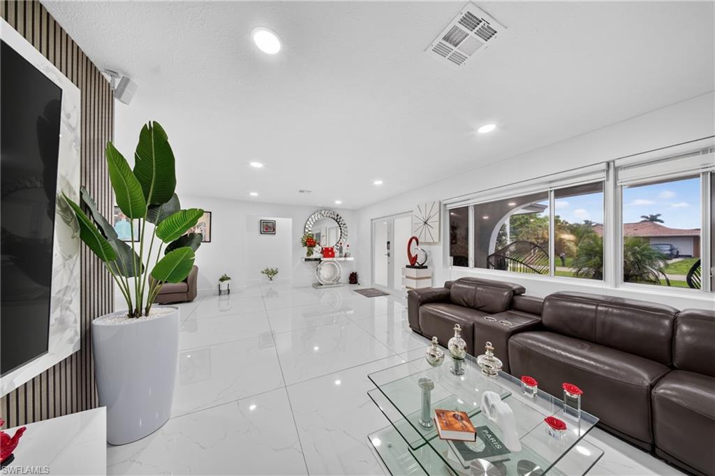 Recessed ceiling lighting, large white tile flooring, expansive windows, white walls, and a decorative wall panel