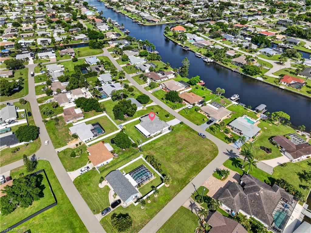 Canal-front community featuring residential properties, mature trees, and paved roads