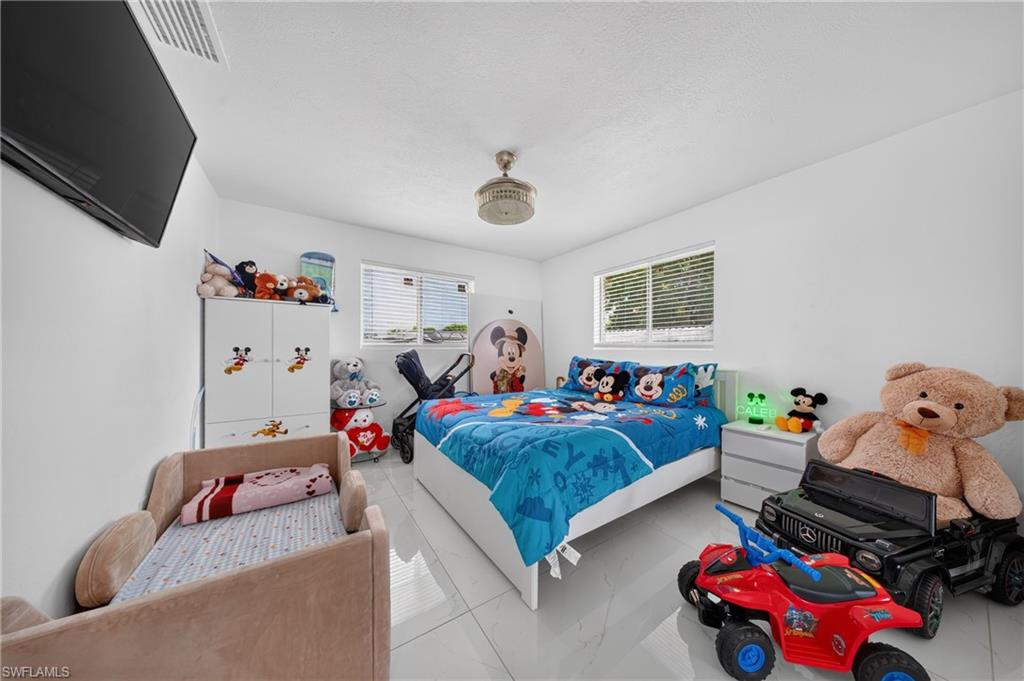 White walls, recessed ceiling fixture, dual pane windows with horizontal blinds, and tile flooring