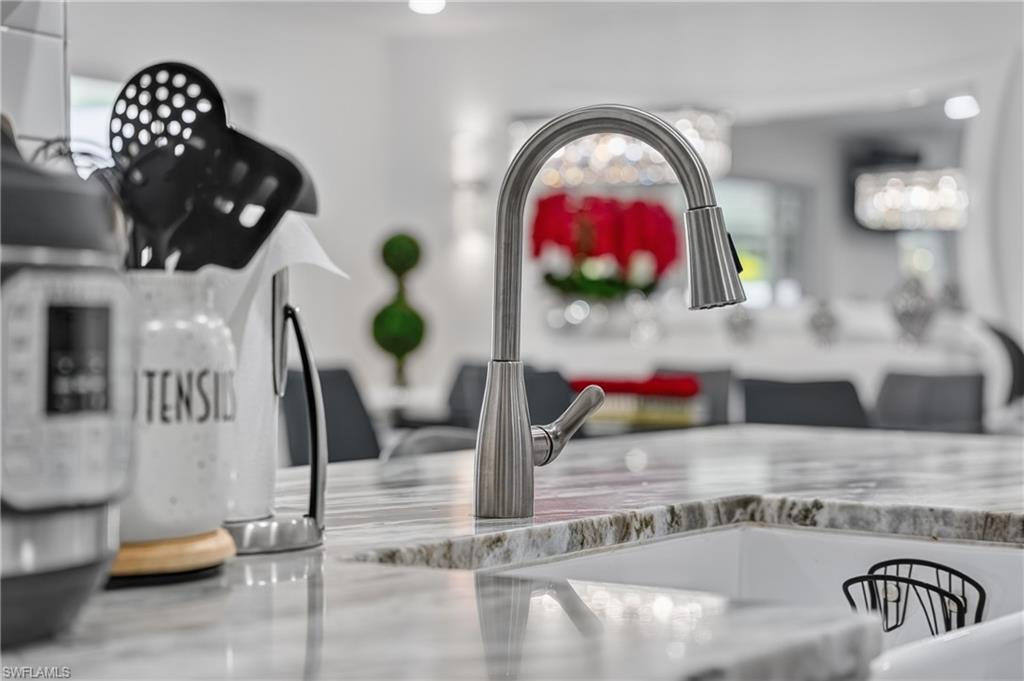 Gooseneck pull-down faucet with a single-handle design, integrated into a white sink basin, set within a polished stone countertop