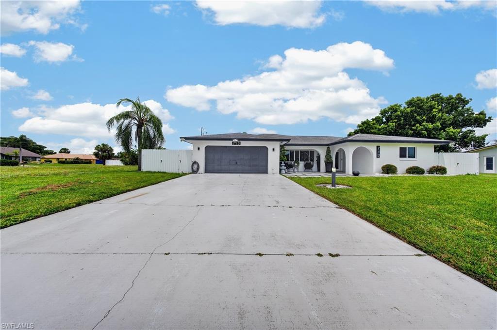 Single-story residence featuring a white exterior, attached garage, and arched entryways