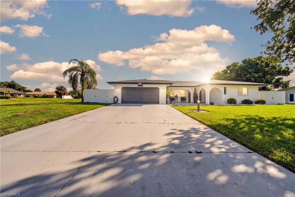 Single-story residence featuring a white exterior, attached garage, arched entryways, and a concrete driveway