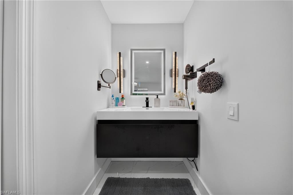 Floating vanity with integrated sink, black cabinet, illuminated mirror, and vertical wall sconces
