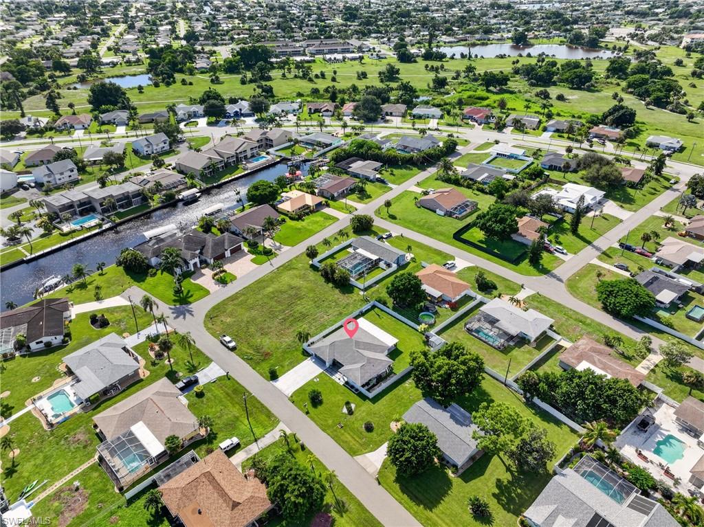 Expansive neighborhood with waterways, green spaces, residential streets, and individual properties featuring swimming pools