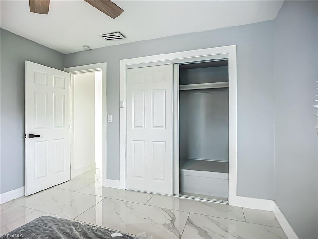 White panel doors, sliding closet doors, wood-finish ceiling fan, and large format floor tiling