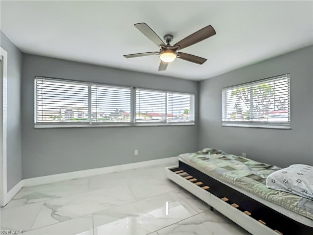 Recessed lighting, wood-finish ceiling fan with light, multiple windows with blinds, light gray wall color, and large format tile flooring