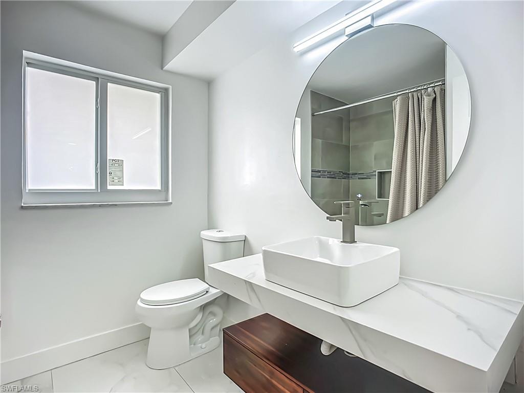Floating vanity with integrated vessel sink, wall-mounted faucet, round mirror, and a window