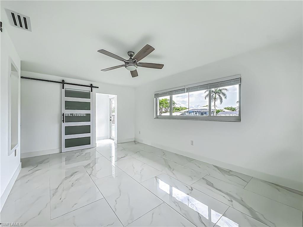 White tile flooring with veining, white walls, and a ceiling fan with wood-finish blades